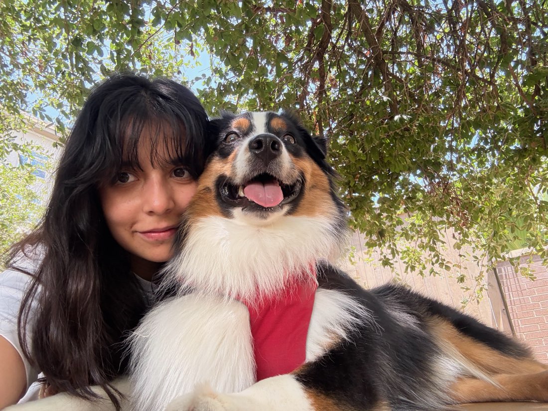 Fangio pressed cheek to cheek with his owner under a shady tree, tongue out